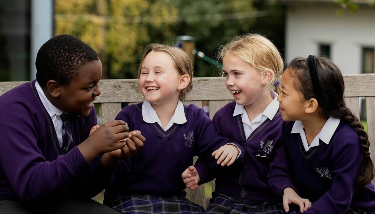 Pupils sitting on the bench, laughing.